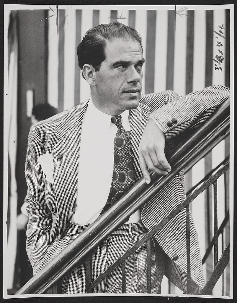 Frank Capra in a checked suit, resting his arm on a railing aboard the Rex, 1937.