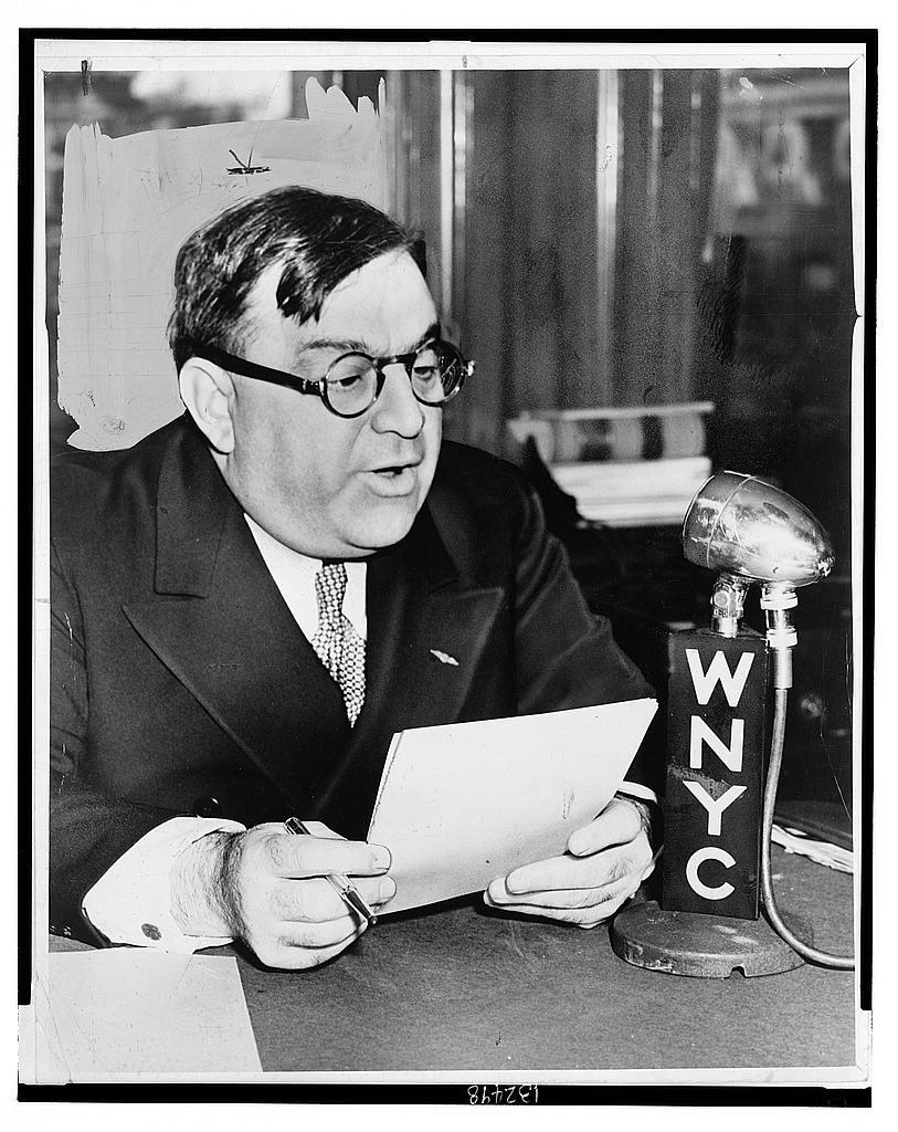Fiorello La Guardia reading a message beside a WNYC microphone.