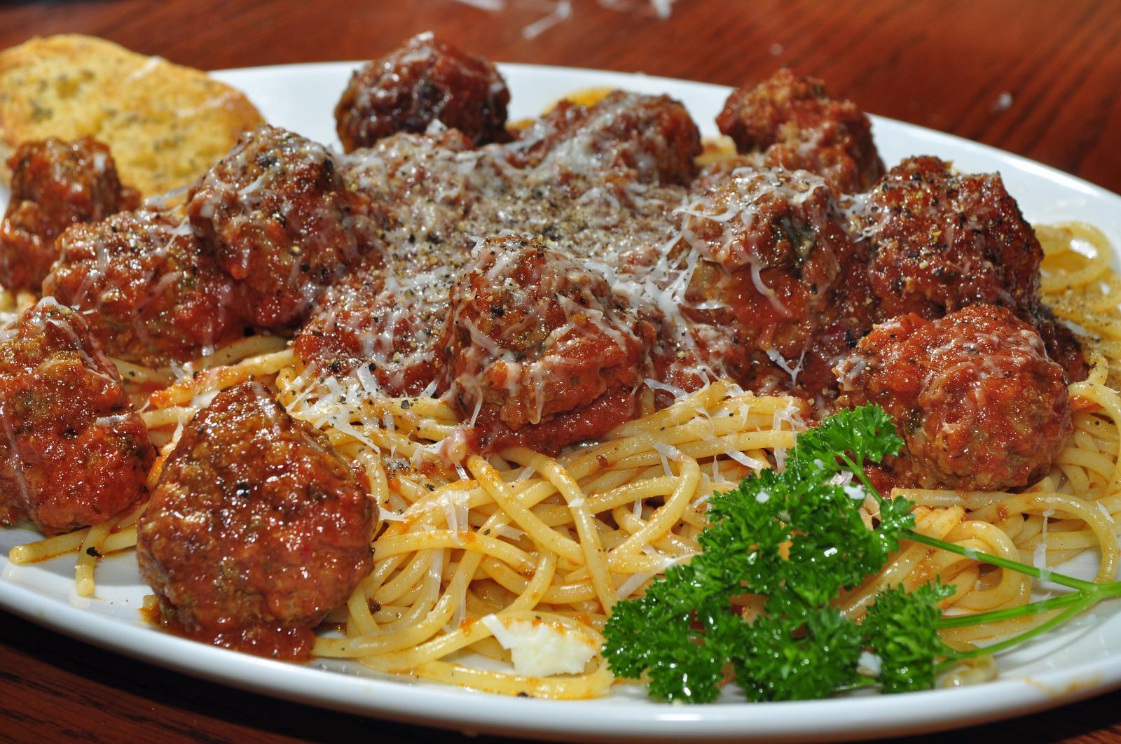 Italian American food: spaghetti and meatballs in tomato sauce with grated cheese, parsley, and garlic bread.